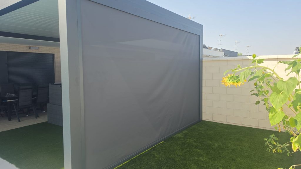 Toldo vertical ZIP Nexus 130 con sistema de guiado mediante cremallera ZIP, diseñado para proporcionar una excelente protección solar, mayor resistencia al viento y un cierre lateral prácticamente hermético. Su tejido técnico Soltis 92 filtra el calor y los rayos UV, reduciendo la temperatura del interior sin perder luminosidad. Gracias a su microperforación, permite mantener la visibilidad hacia el exterior durante el día, aportando privacidad, confort térmico y un diseño moderno, ideal para terrazas, porches, pérgolas y grandes ventanales. motorizado